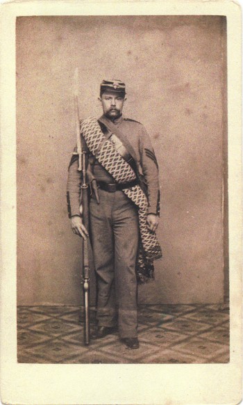 Thomas Lord, Jr., served in the 7th's engineer company; his hat displays the ordnance bomb insignia of that company on its front. He carries his personal blanket. Note that his belt is of dark leather; the other companies in the 7th wore white buff belts. 